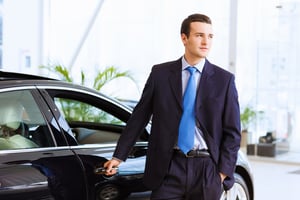 Image of handsome young businessman in suit standing near car